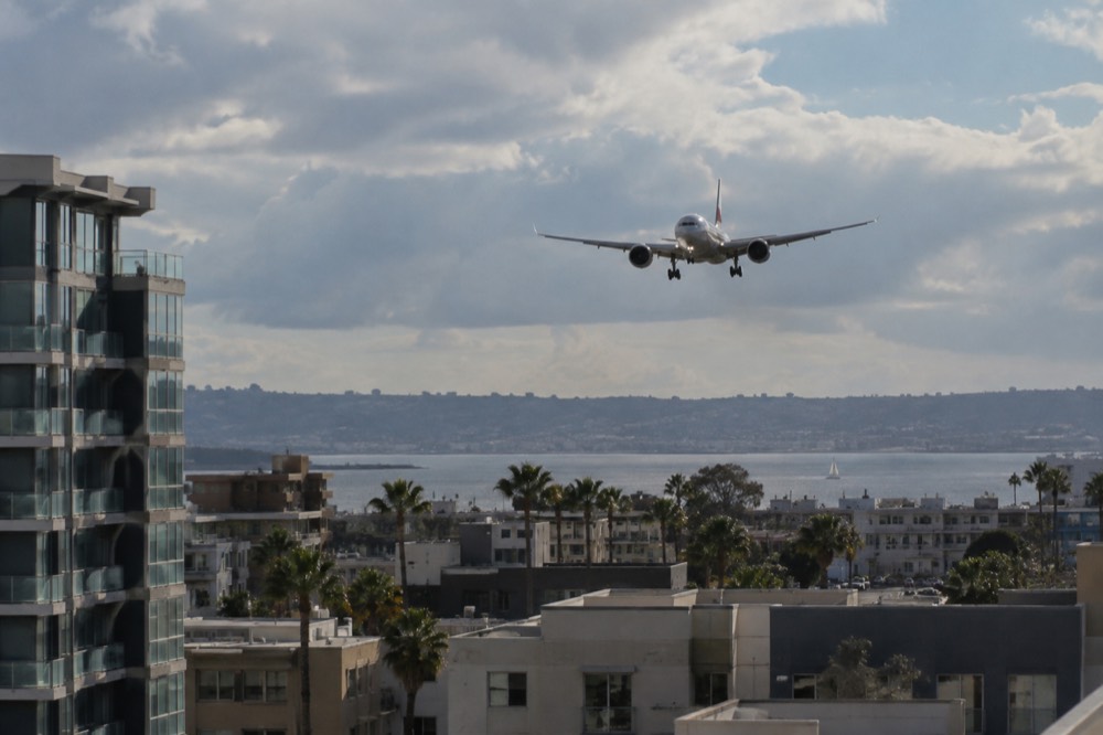 A commercial airliner on approach over San Diego rooftops near the airport