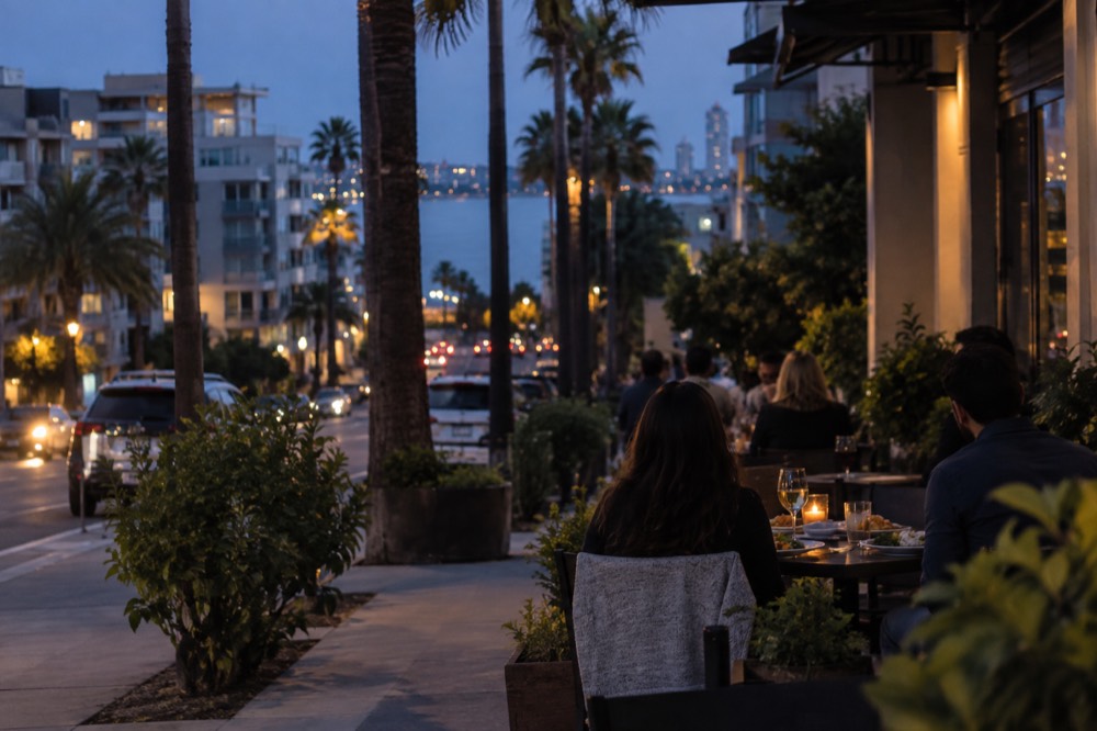 A quiet neighborhood sidewalk cafe table with plates of food in evening light