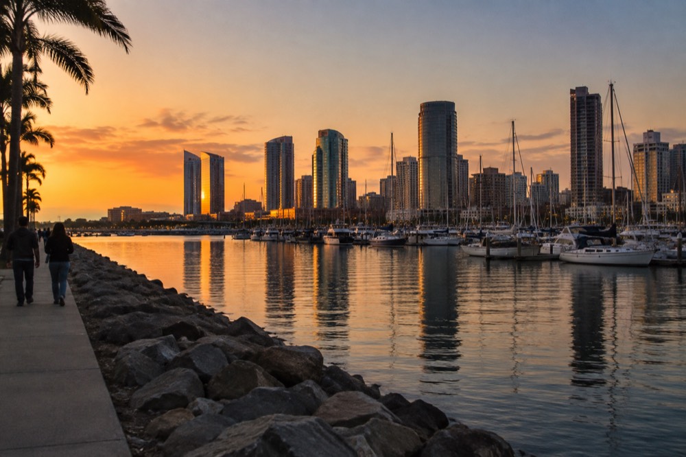 An evening view of the San Diego waterfront with masts and city lights reflected in the bay