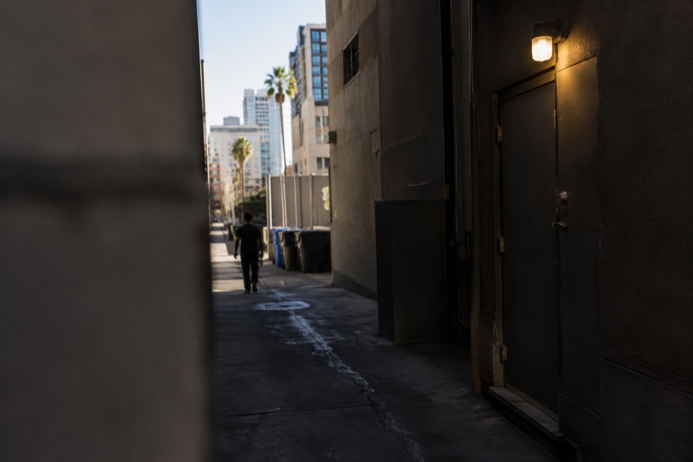 A narrow unmarked alley entrance lit by a single bulb beside a closed door