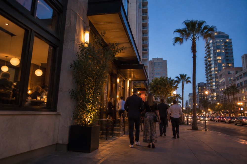 Late afternoon light on a downtown San Diego street with diners walking toward restaurant entrances