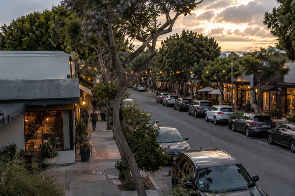 Storefronts and string lights along a neighborhood street at dusk