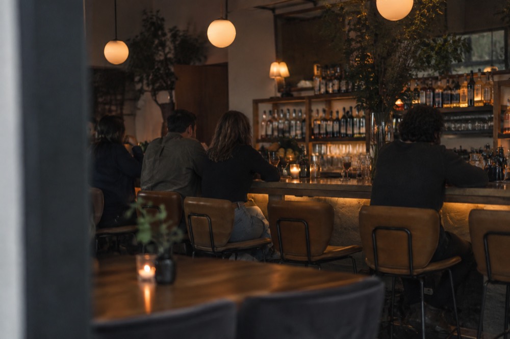 A cocktail bar interior with warm lighting and stools along the counter