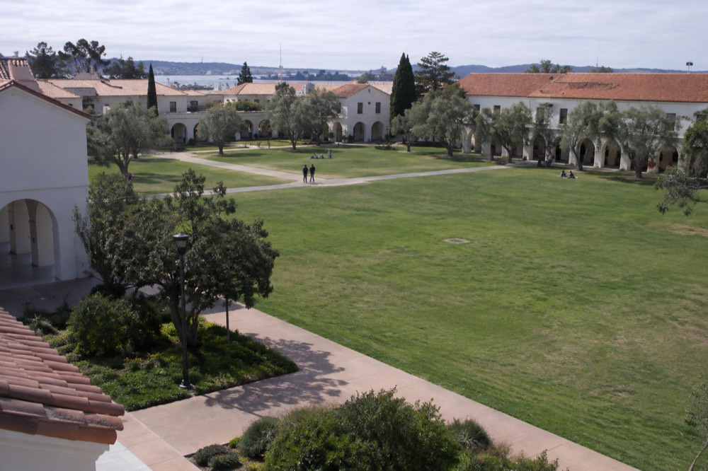 Wide green lawn between historic white buildings at Liberty Station