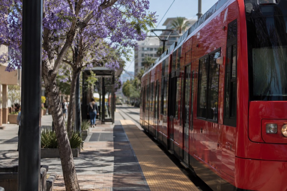 Red trolley car at a station platform beside a city street