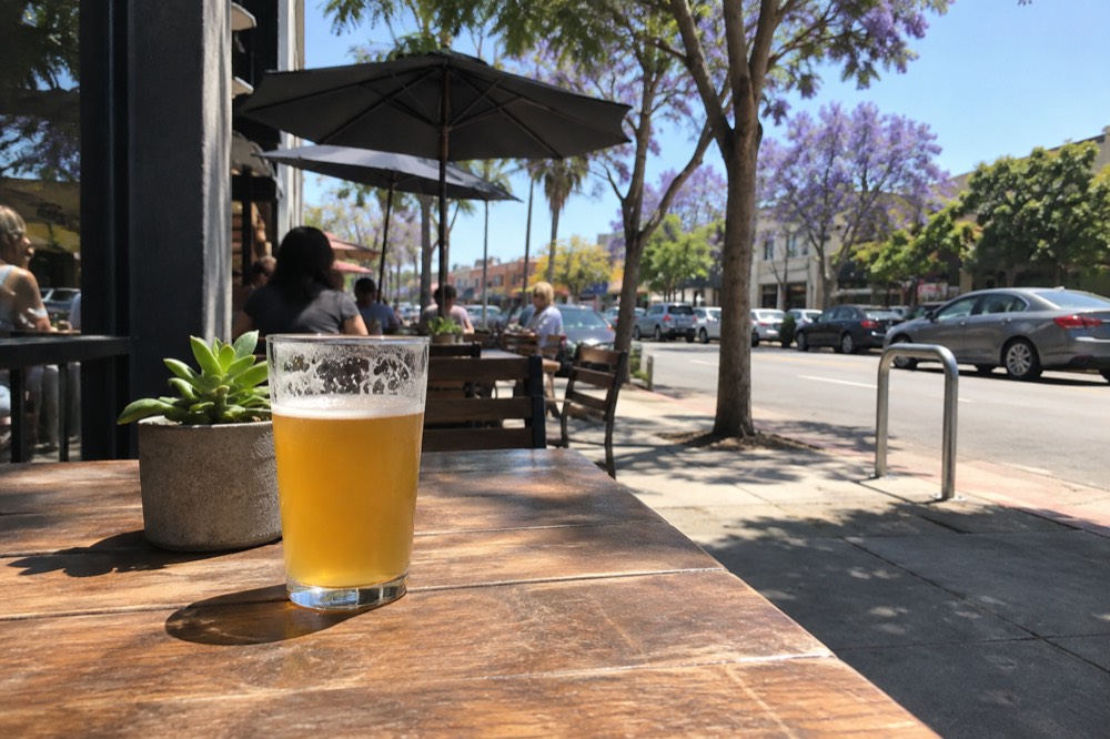 Sidewalk tables outside a corner brewery on a busy North Park block