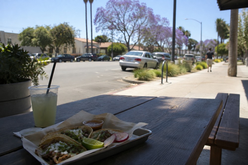 Tacos on a tray on an outdoor picnic table beside a mural wall