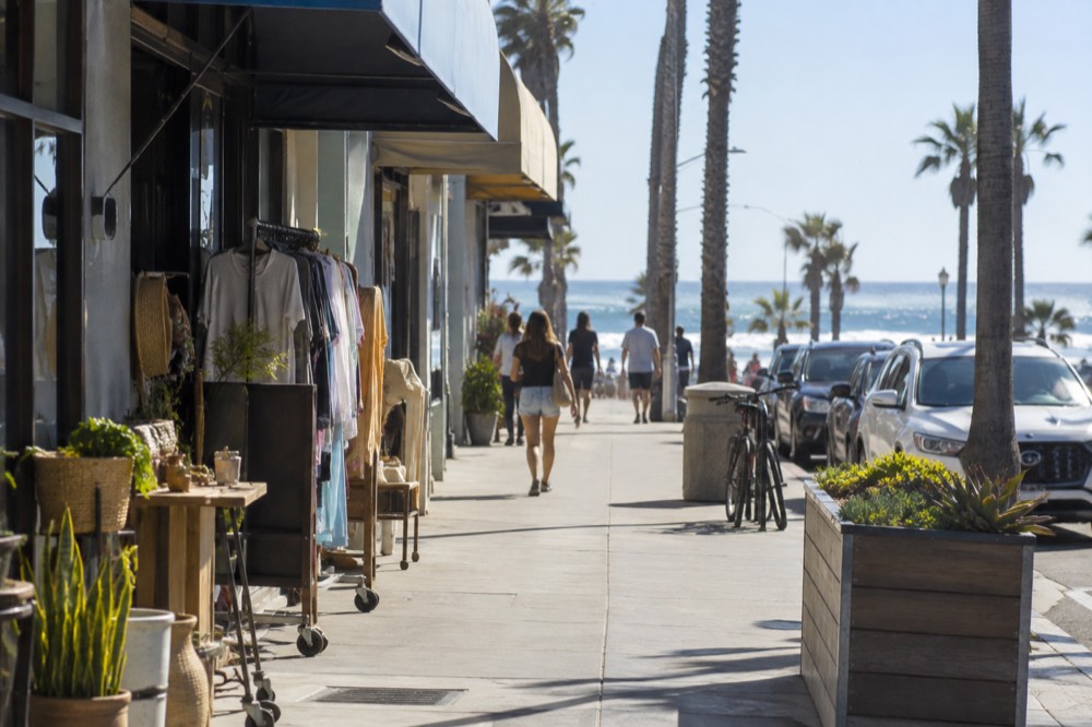 Newport Avenue storefronts with awnings and sidewalk displays along the Ocean Beach main street