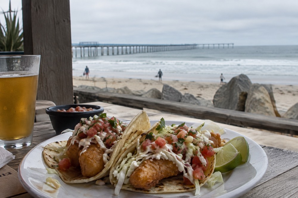 Fish tacos on a plate at an outdoor table near the Ocean Beach pier
