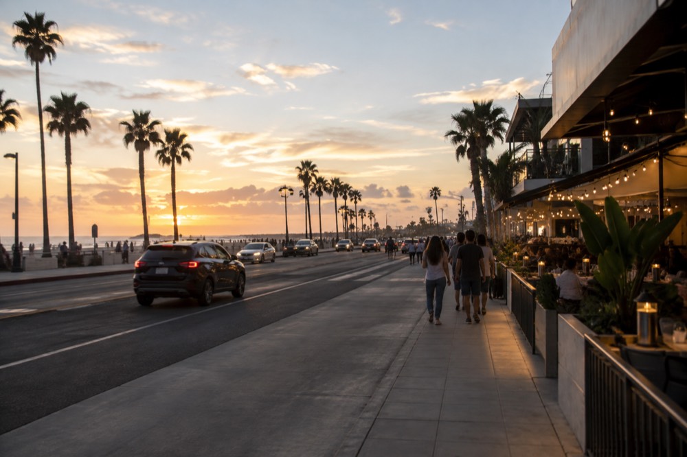 Evening street scene with lit storefronts and outdoor tables along a busy avenue