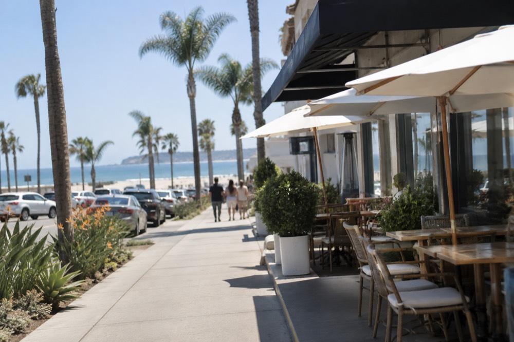 Palm-lined Orange Avenue with sidewalk tables and storefronts in afternoon light