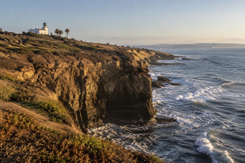 Old lighthouse structure on a hilltop with the bay and ocean in the distance