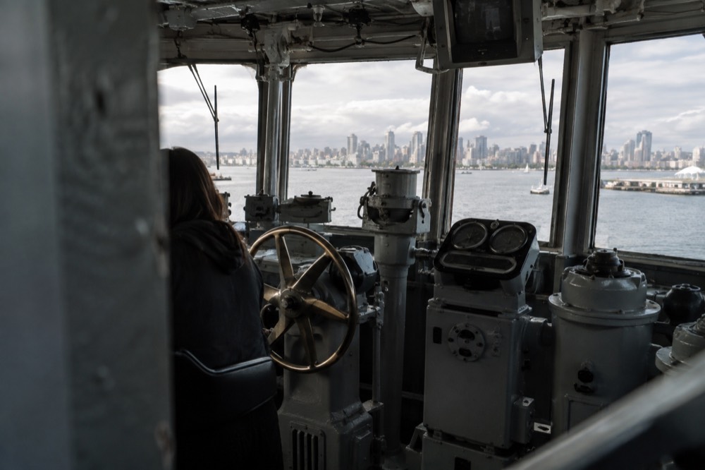 The ship's bridge interior with helm controls and windows overlooking the bay
