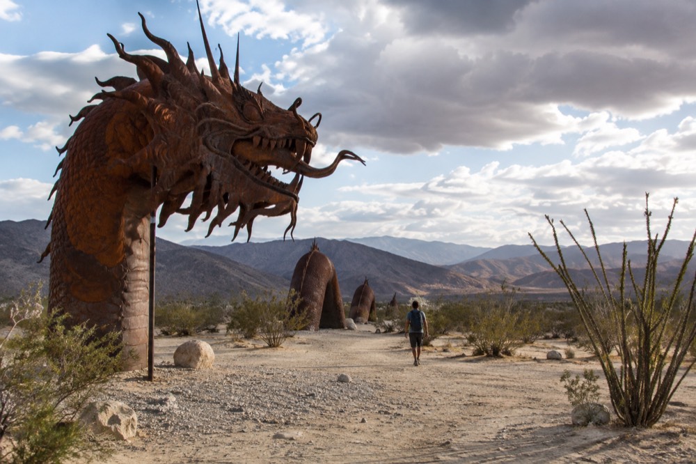 Tall metal sculpture of a serpent standing in an open desert field