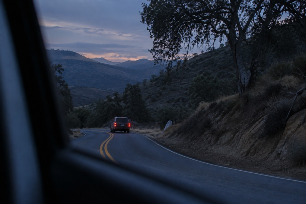 A winding two-lane road through oak-covered mountains