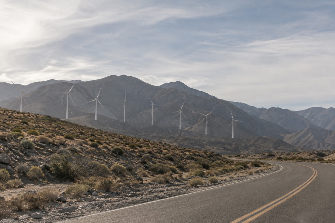 Desert hills with windmills rising along a mountain pass under a wide sky