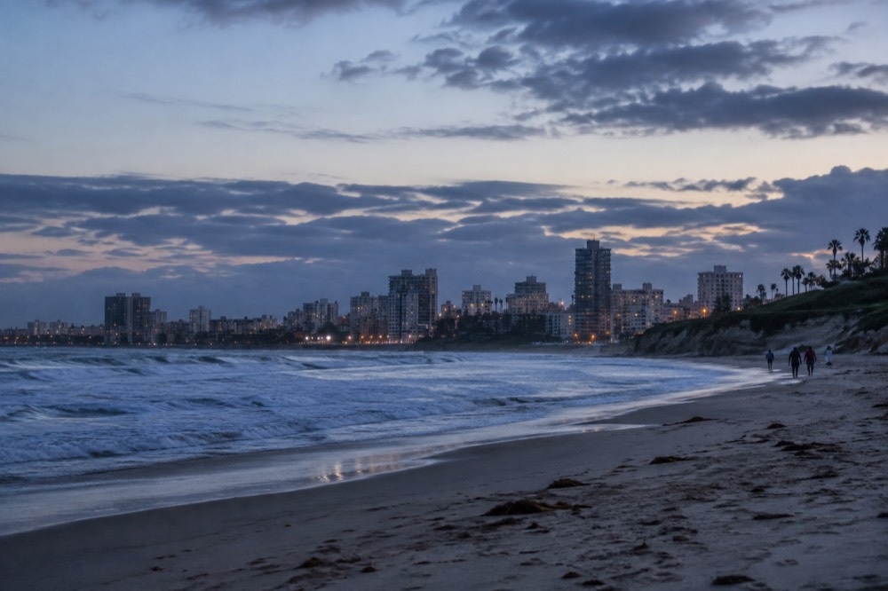 Wide sandy beach with gentle waves and rocky bluffs along the San Diego coastline