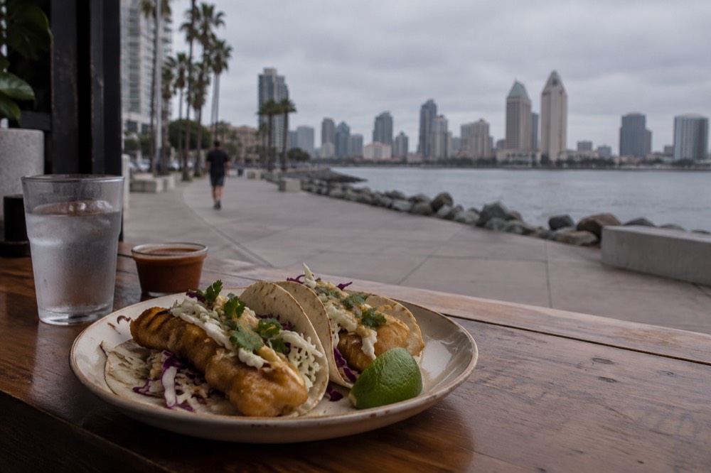 A plate of battered fish tacos with cabbage and lime on a wooden counter