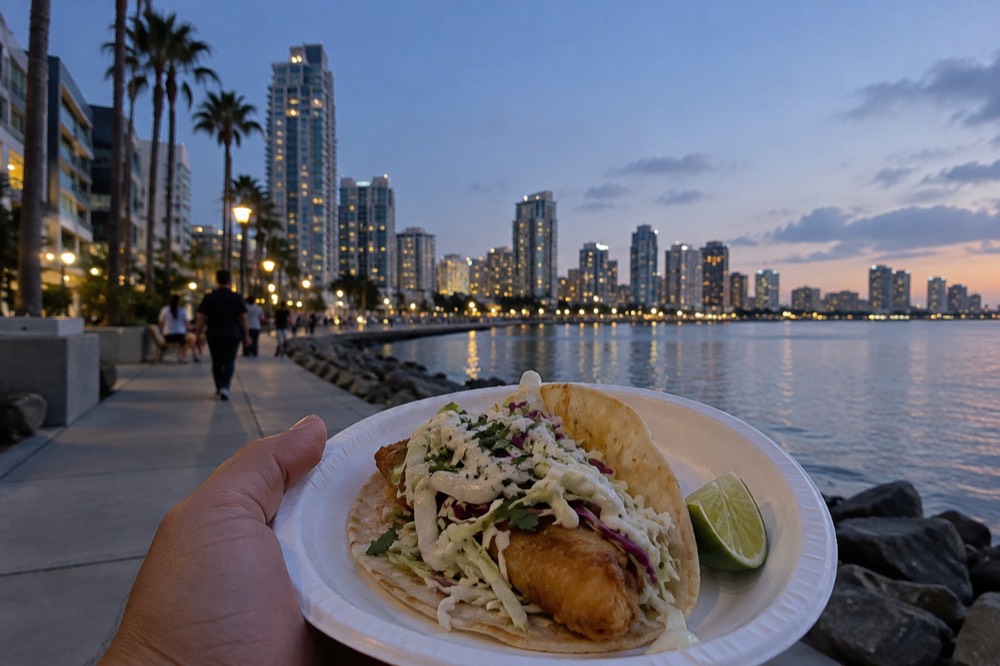 A Baja-style fried fish taco with cabbage and lime on a paper plate