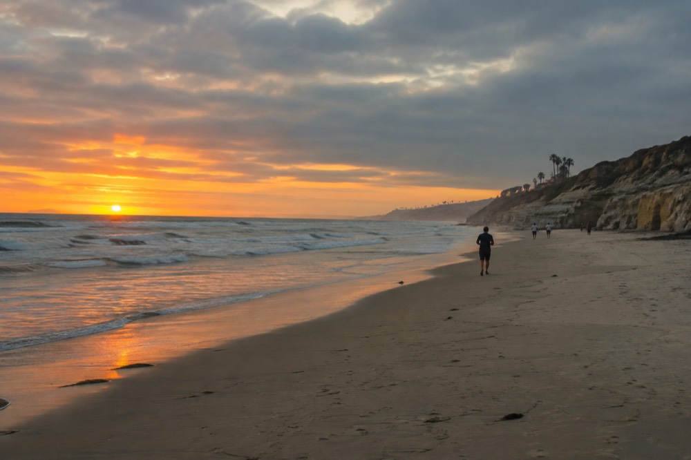 Wide view of a Pacific beach in San Diego with cliffs and waves at golden hour