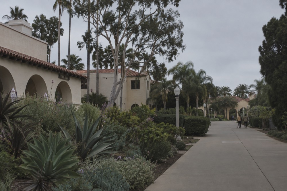Gardens and Spanish colonial style buildings along a walkway in Balboa Park