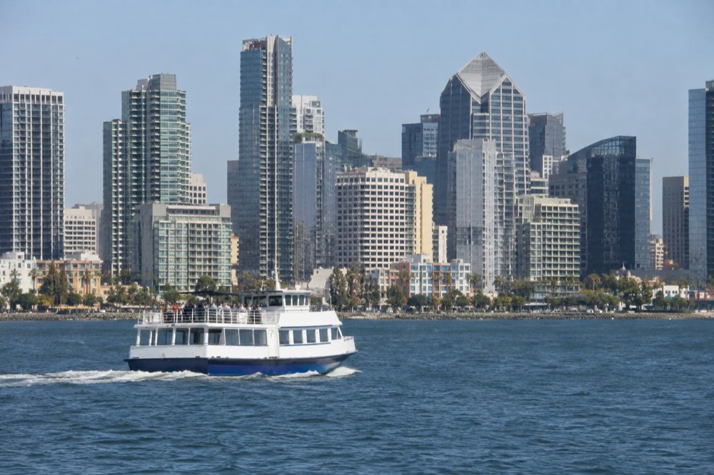 Sightseeing boat cruising on San Diego Bay with the downtown skyline behind it