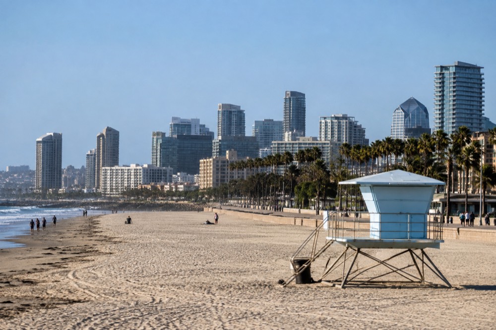 A lifeguard tower overlooking a wide sandy beach with a walking path behind it