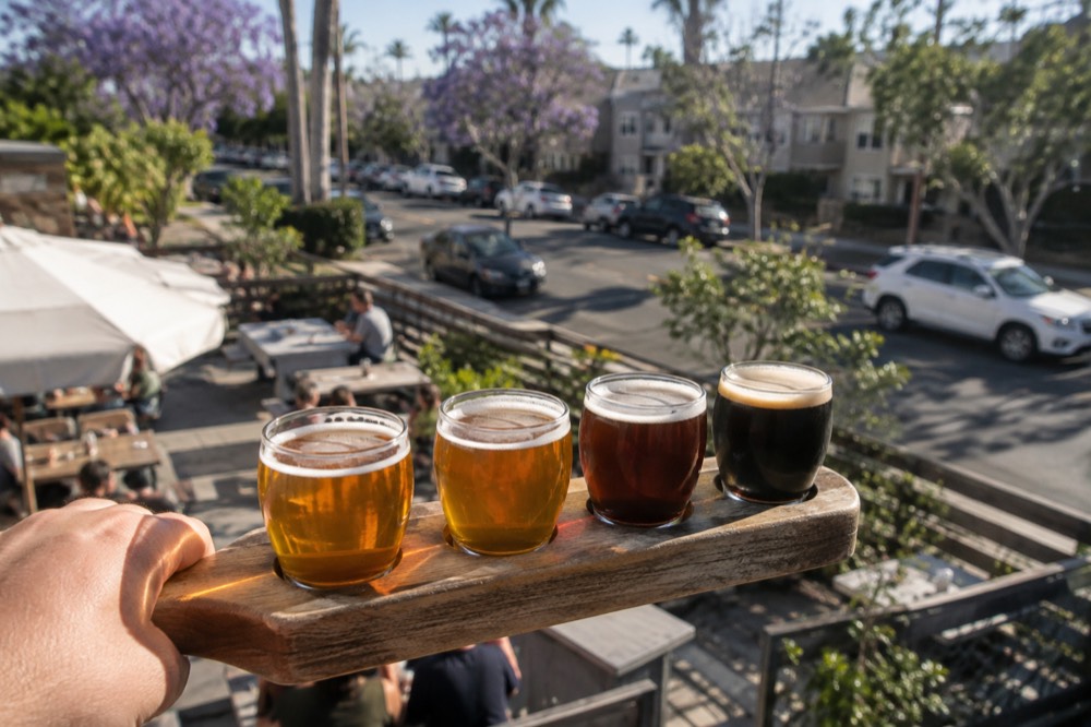 A customer holding a tasting flight tray with four small glasses of beer