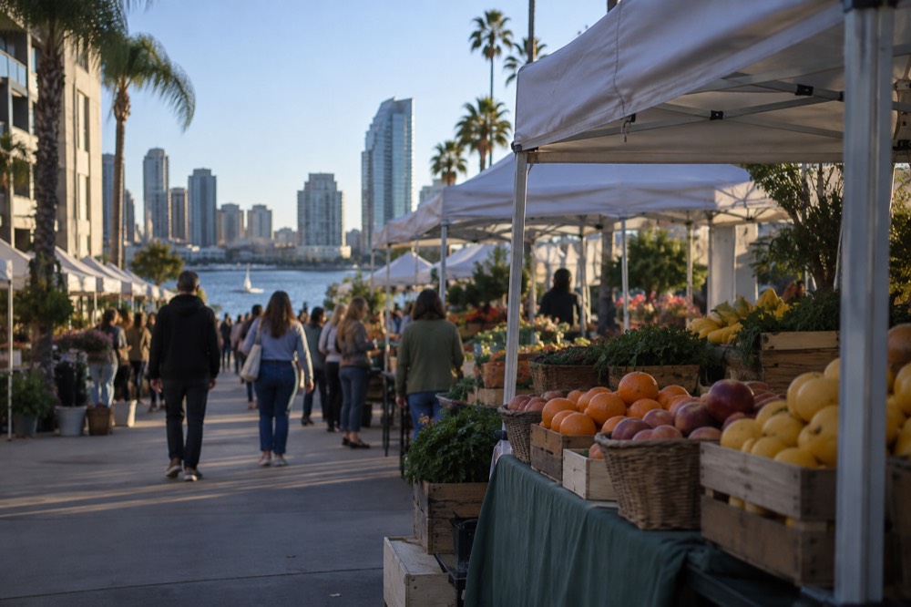 Produce stalls with fruit baskets under white canopies on a sunny street