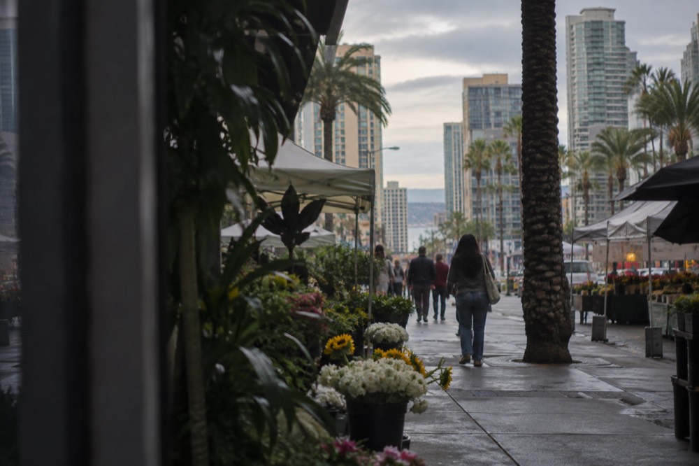 A market street under a grey morning sky with the sun breaking through