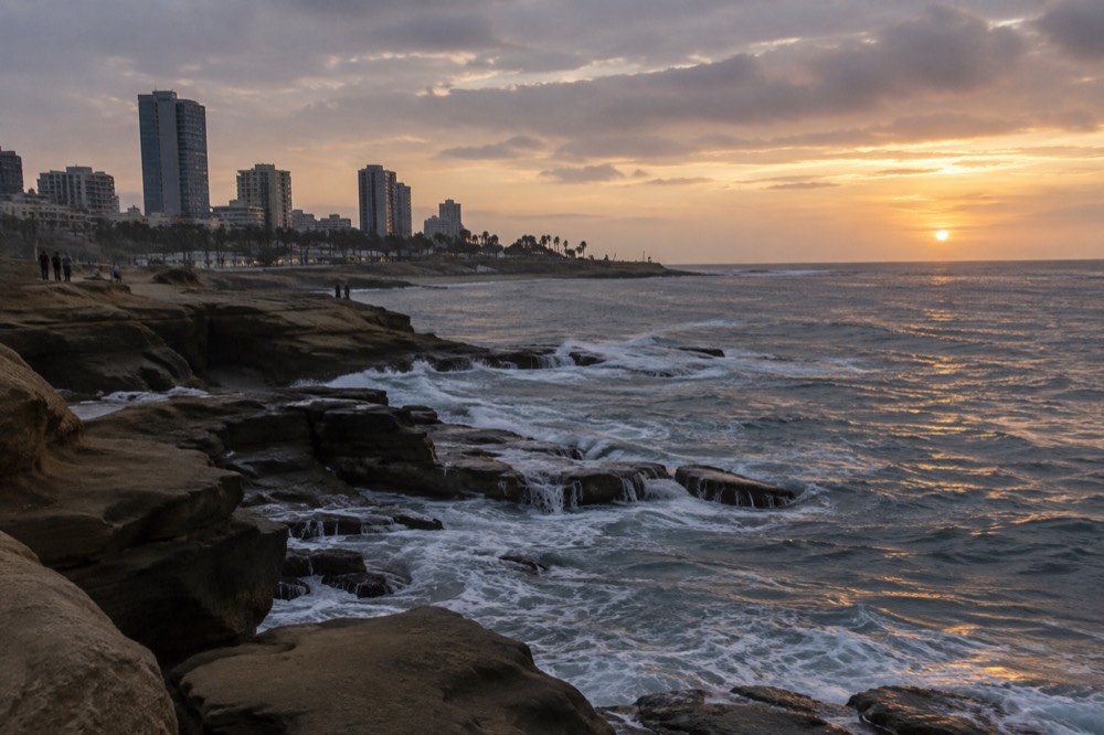 Rocky cove at golden hour with waves breaking around sea-carved stone