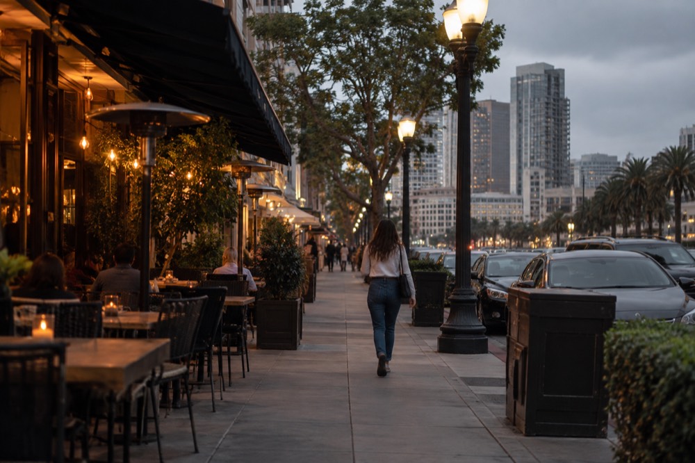Outdoor dining tables on a lamp-lit historic street in the evening