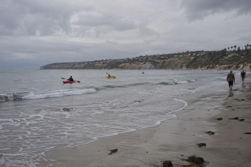A sheltered sandy bay with gentle waves and kayaks near shore