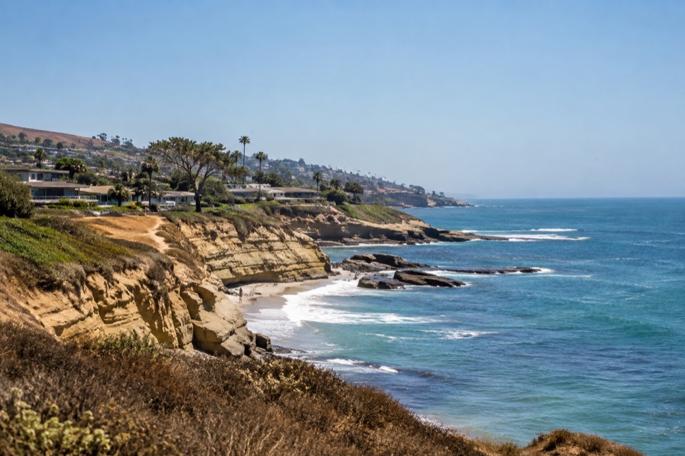 Clear August sky over La Jolla coastline with turquoise water and sandstone bluffs