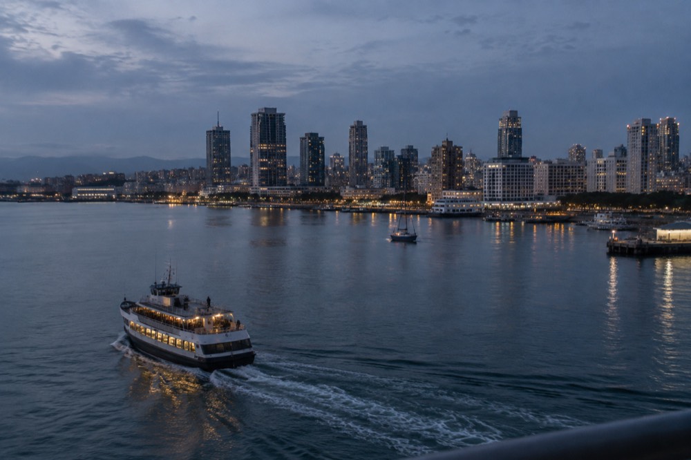 Ferry crossing a calm San Diego Bay toward the downtown skyline at dusk