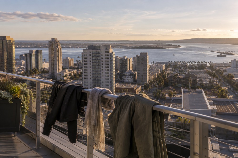 Jackets and scarves hanging on a railing with a sunny San Diego bay in the background