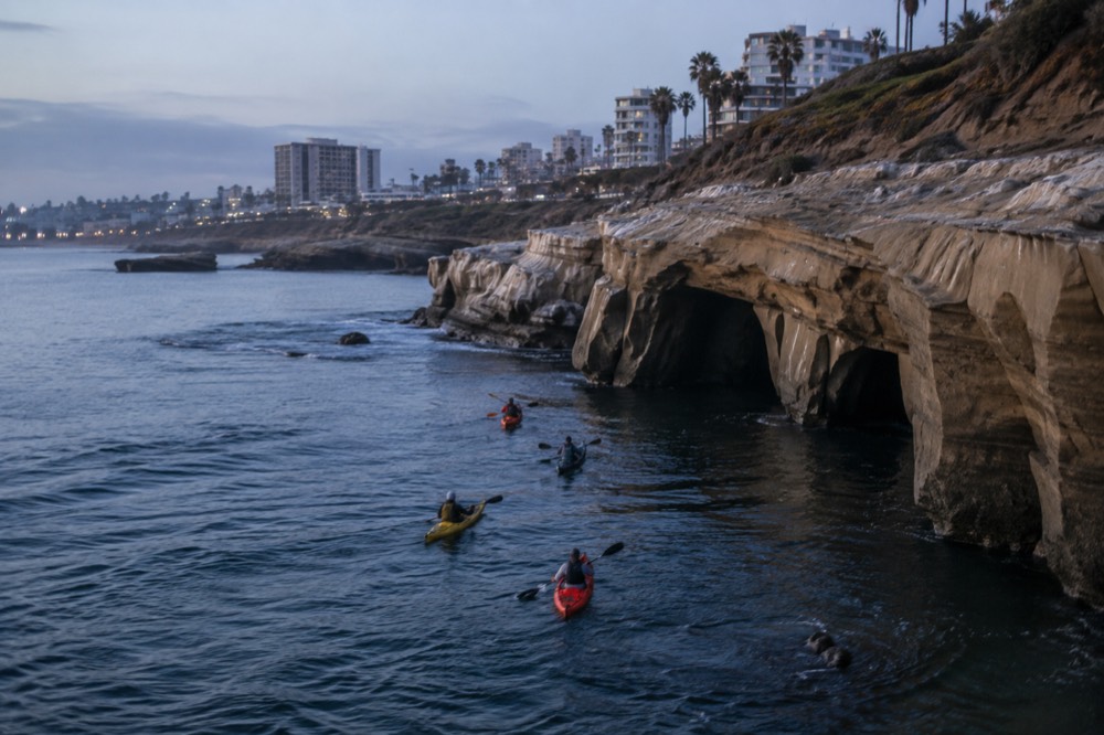 Kayakers paddling toward the sea caves at La Jolla Cove on a calm morning
