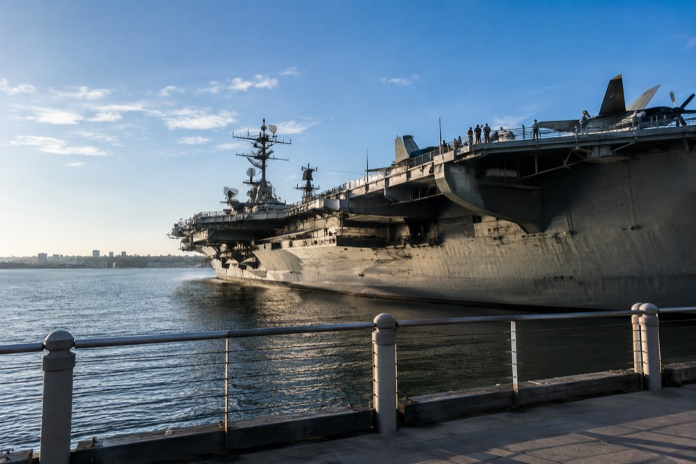 Aircraft carrier museum ship moored at the downtown waterfront with visitors on the flight deck