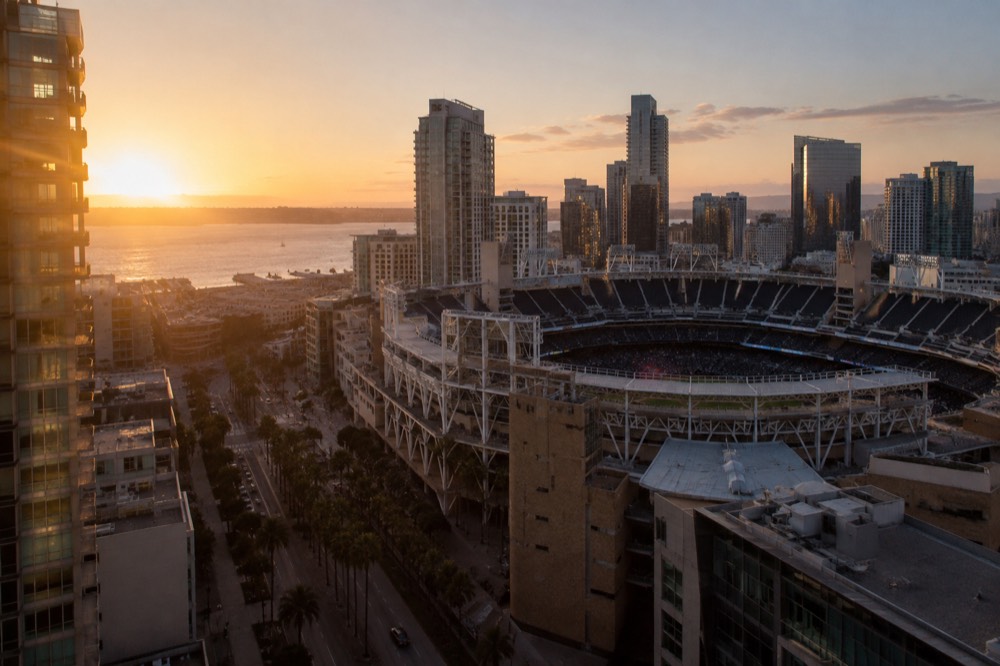 Baseball stadium exterior with downtown buildings visible behind it at dusk