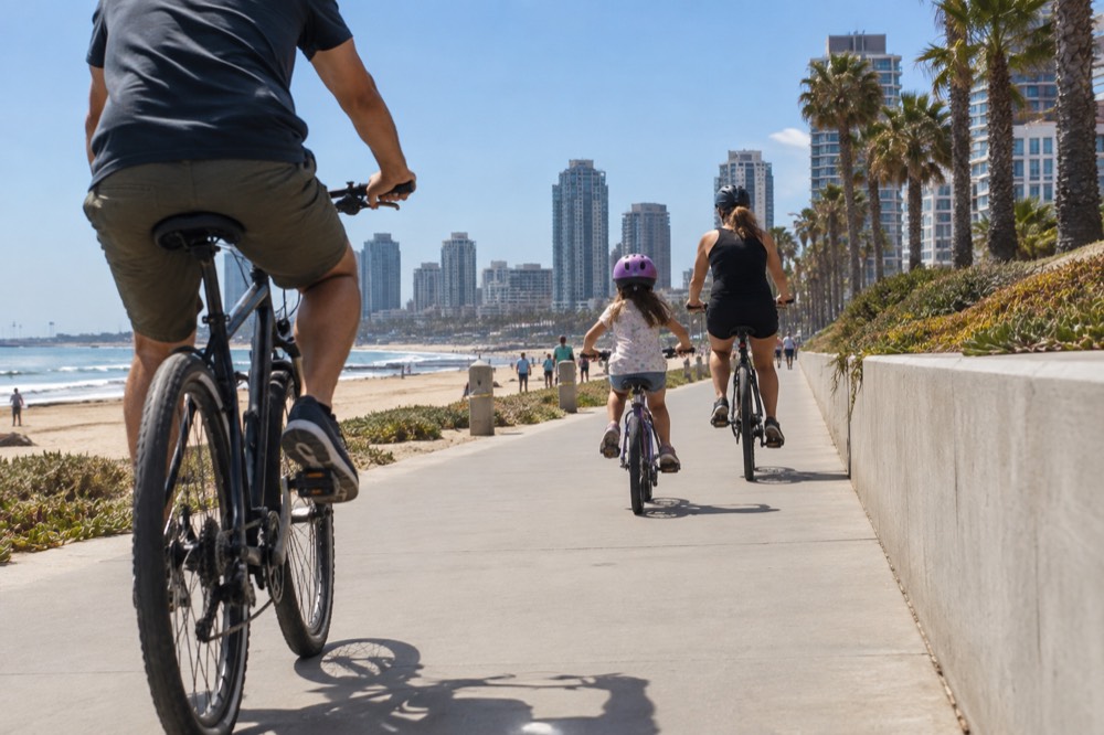 A family bicycling together on a flat beach boardwalk path